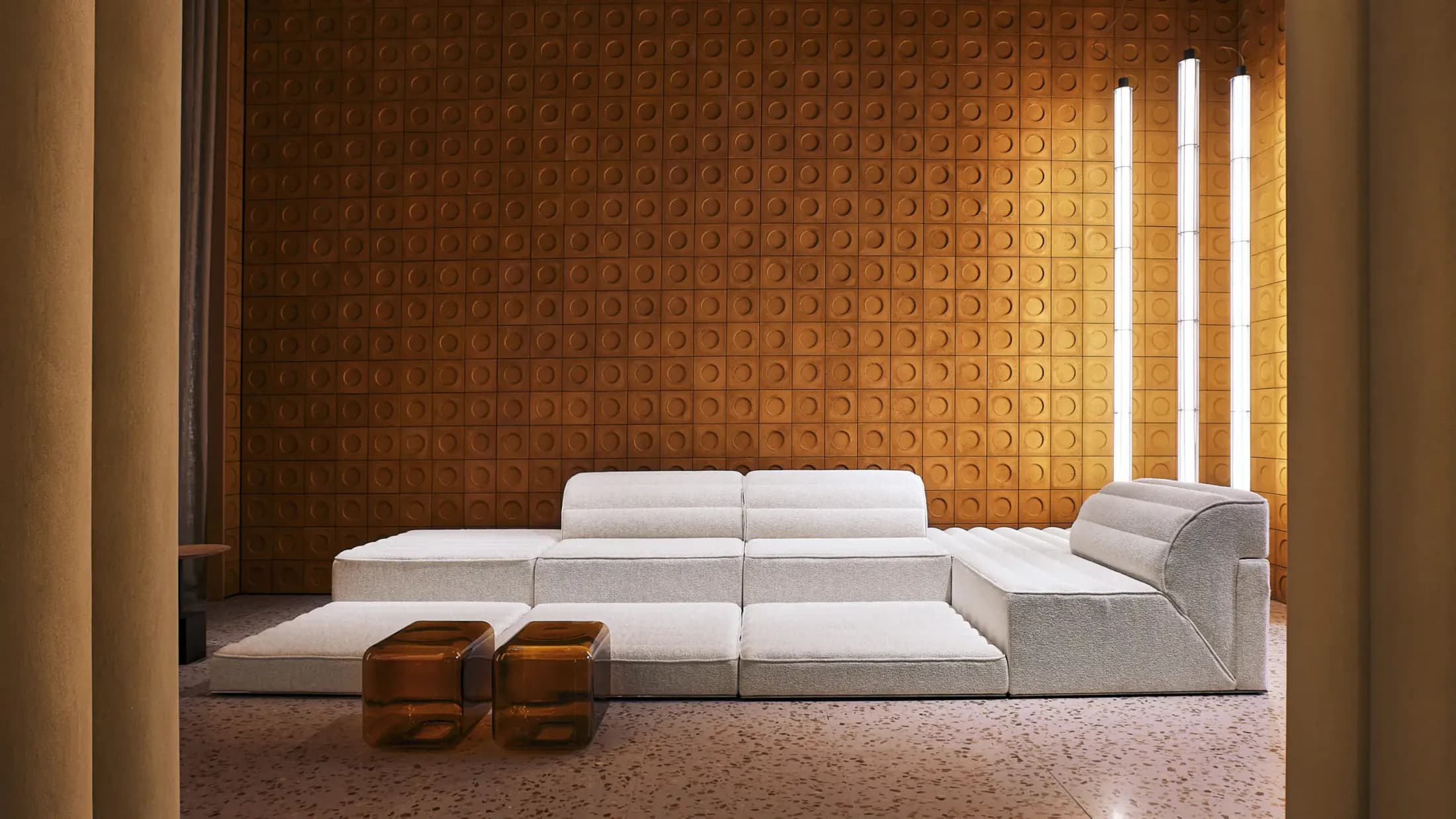 Orange relief Cimento wall with a pale sculptural sofa
